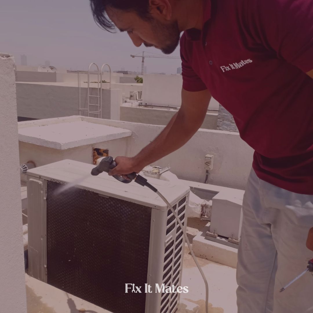 Technician from Fix It Mates cleaning an outdoor Air Conditioning unit on a rooftop.