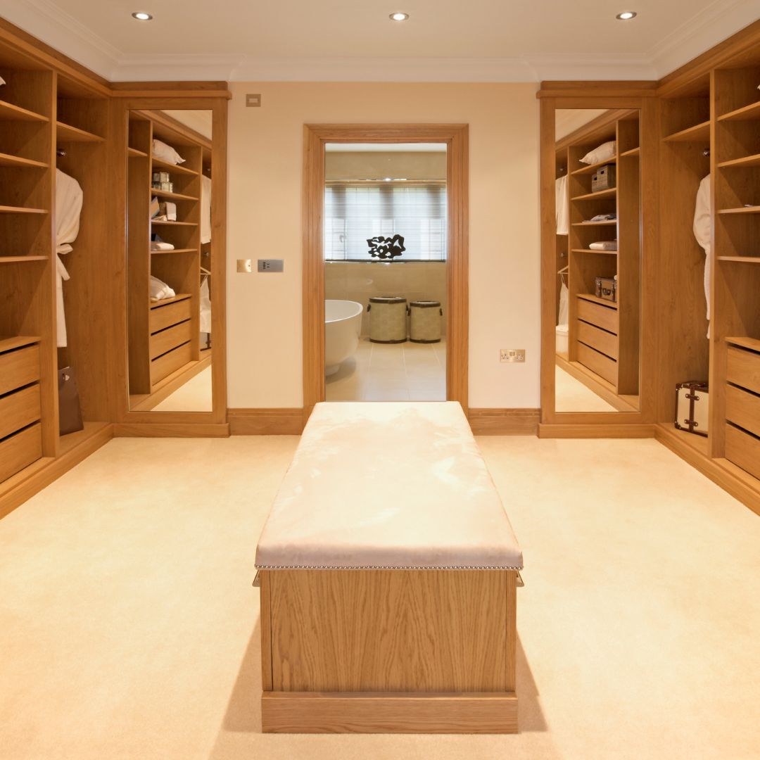 A custom walk-in closet designed and built by Fix It Mates, featuring spacious shelves, hanging rods, and drawers with a polished wooden finish, providing an organized and luxurious storage solution in a contemporary home setting.