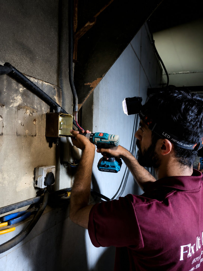 Fix It Mates electrician checking DB board and circuit breakers during electrical maintenance service in Dubai.